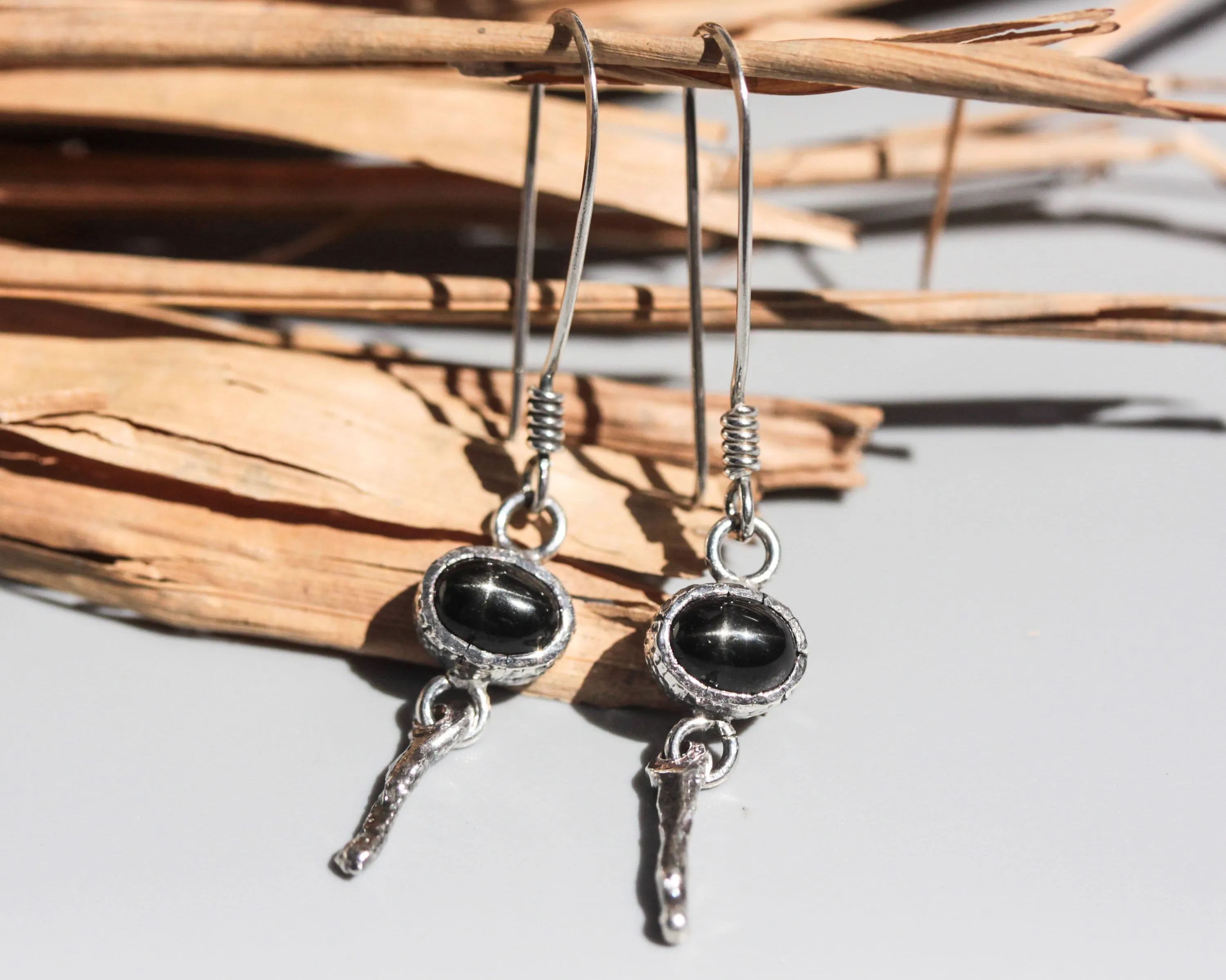 Oval Star Diopside Earrings, featuring a silver bezel setting and silver sticks and hooks on the top